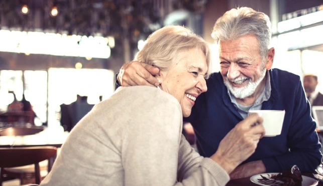 Man and woman laughing over a cup of coffee